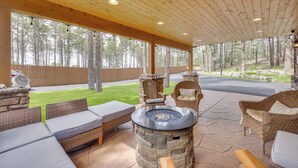 Un patio al aire libre con piso de piedra, mobiliario de mimbre y una chimenea de piedra.