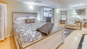 Un dormitorio con cama, una silla, un escritorio y un espejo.