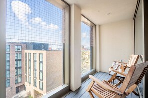 Enjoy the city view from this balcony with a bench and table.