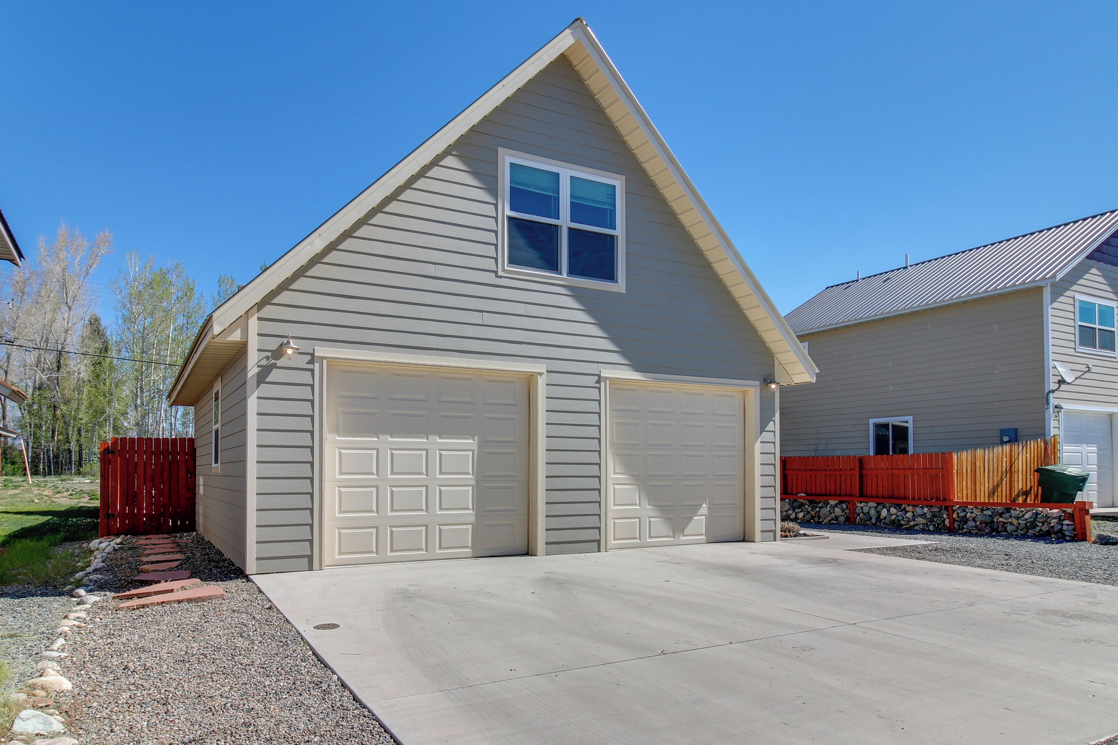 A single-story building with a garage, a small window, and a red fence.