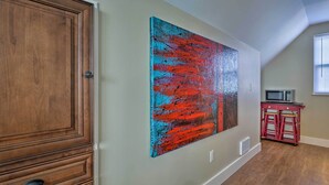 A hallway with a wooden door, a large abstract painting, a microwave, and a small red stool. - Gunnison Studio w/ Shuttle: 30 Mi to Crested Butte (Gunnison)