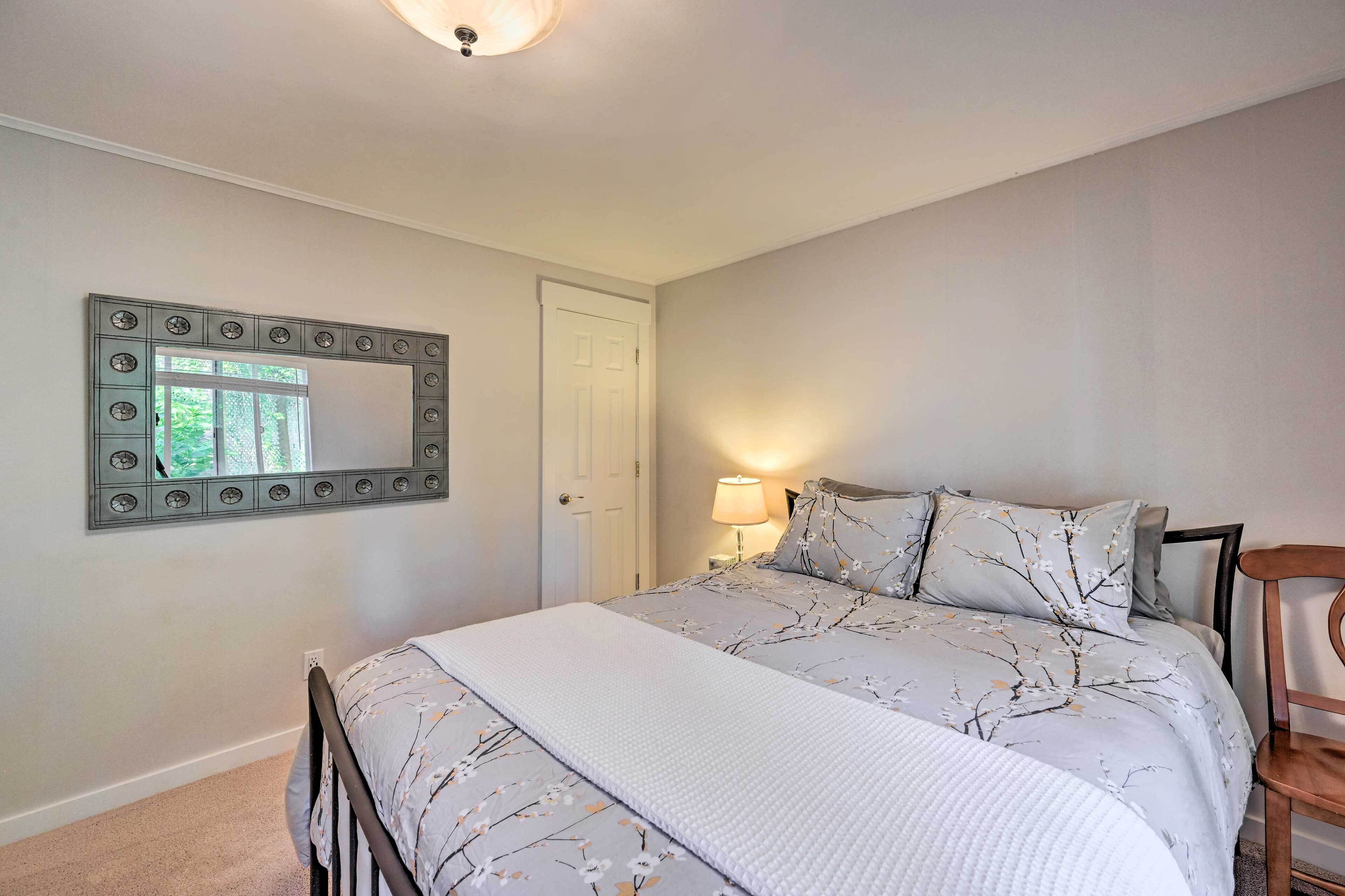 Um quarto com uma cama, um espelho, uma porta e uma luminária.