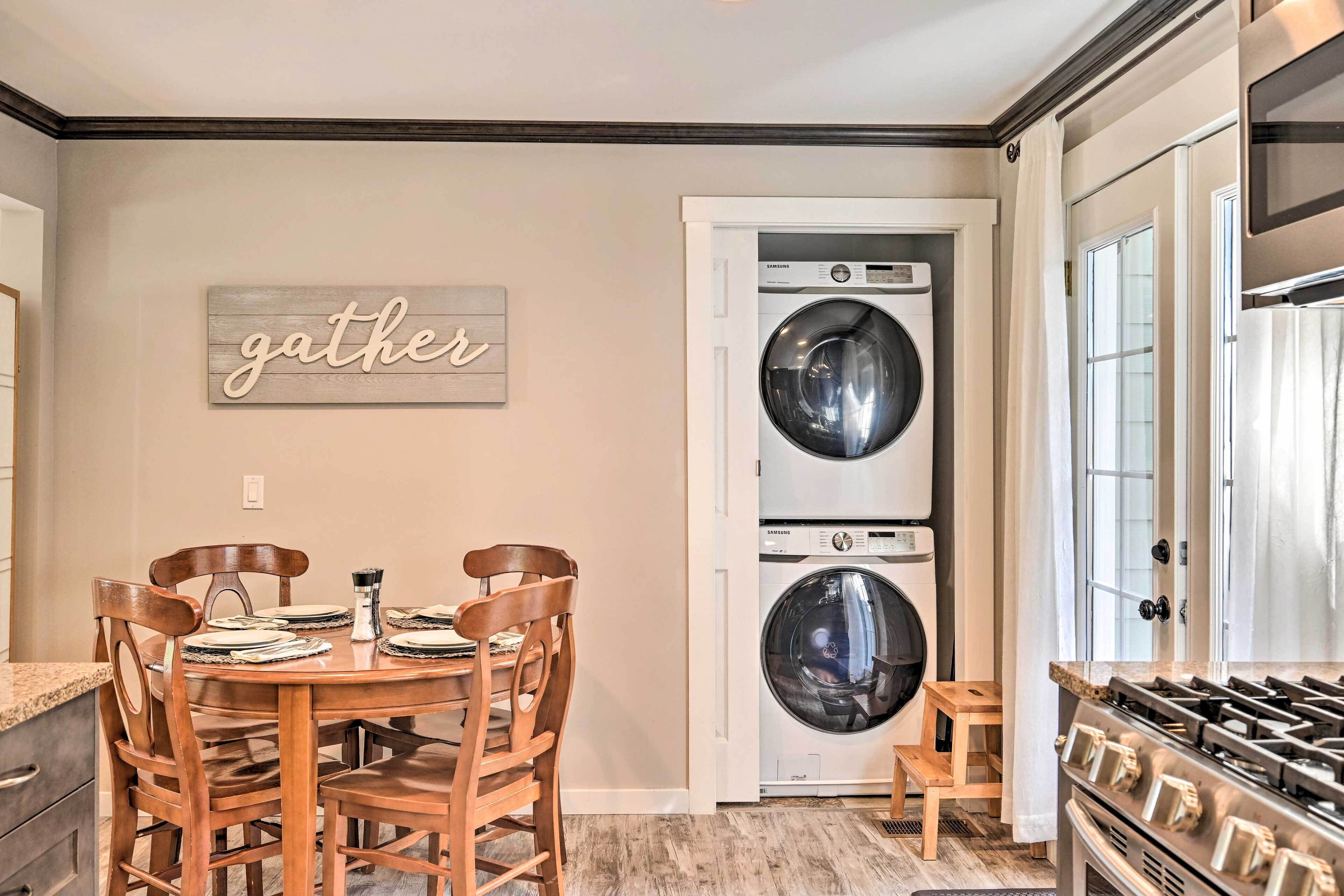 A kitchen with a double-door washer and dryer, a wooden dining table with chairs, and a gas stove.