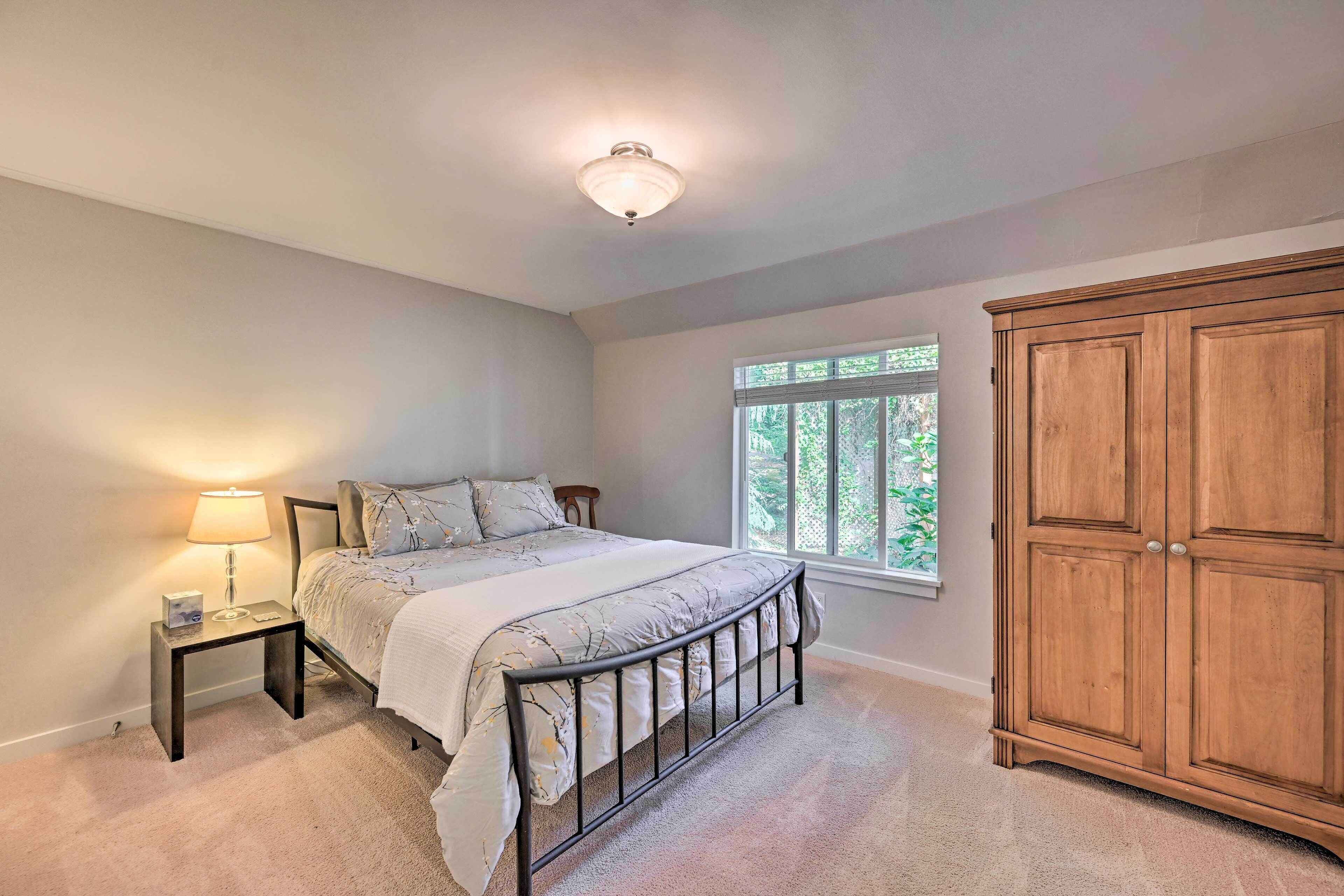 A bedroom with a bed, nightstand, lamp, window, and wardrobe.