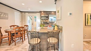A modern kitchen with a central island, wooden dining table, and chairs. - Family-friendly Kirkland Home ~ 1 Mi to Downtown (Kirkland)
