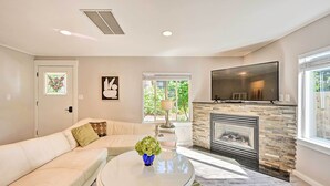 A modern living room with a stone fireplace, a large flat-screen TV, and a comfortable sofa. - Family-friendly Kirkland Home ~ 1 Mi to Downtown (Kirkland)
