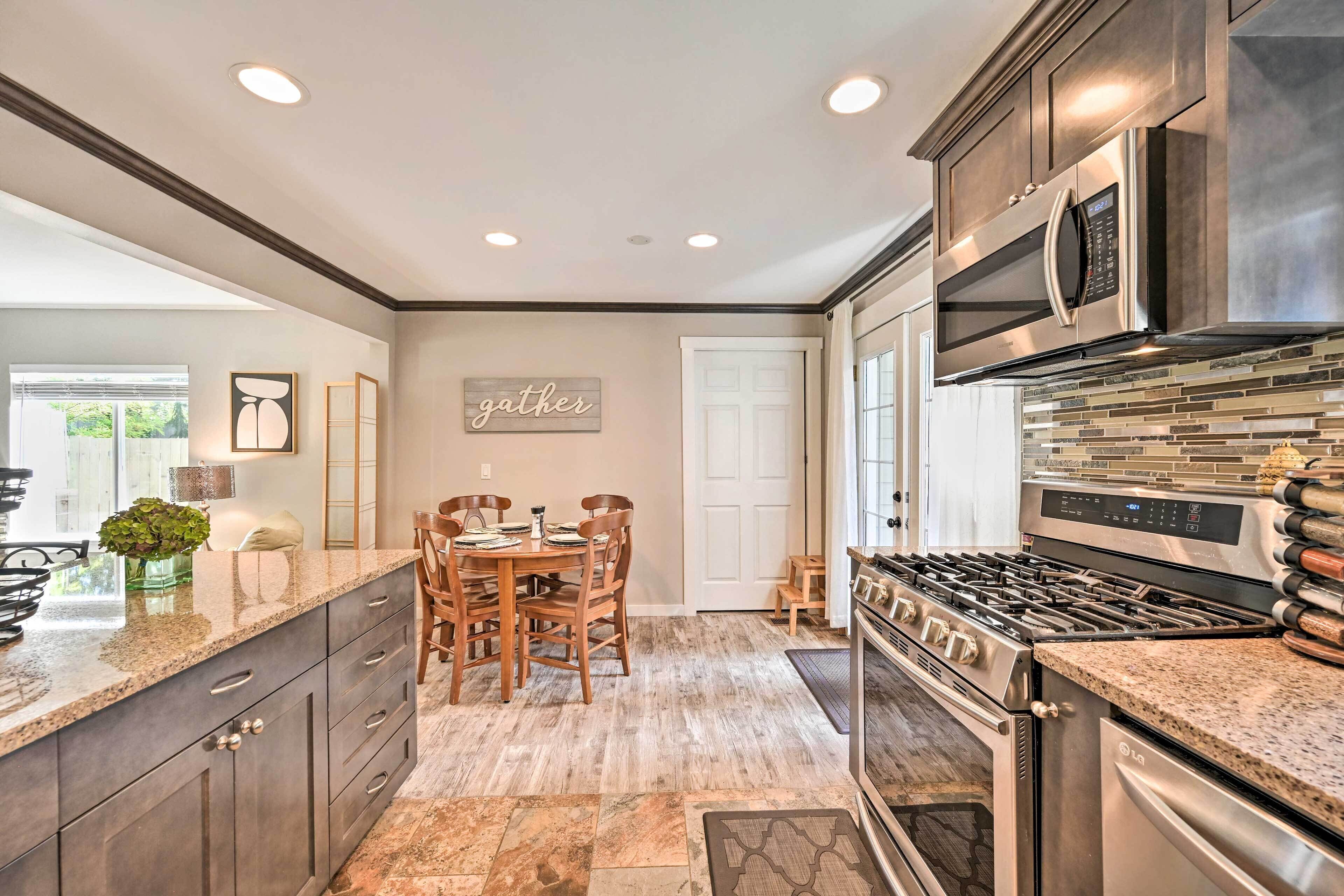 A modern kitchen with granite countertops, stainless steel appliances, and a dining area with wooden chairs and a table.