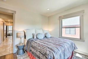 A bedroom with a bed, pillows, a lamp, a window, and a door leading to another room. - Luxe Home w/ Backyard Oasis ~ 1 Mi to Midtown (Reno)