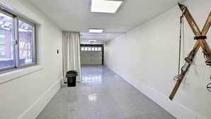 Un pasillo con una ventana, un cubo de basura, una lámpara en el techo y una estructura de madera en la pared.