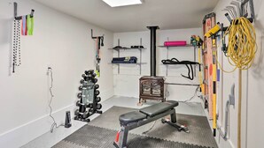Un gimnasio en casa con banca, soporte para pesas y diversos equipos de ejercicio.