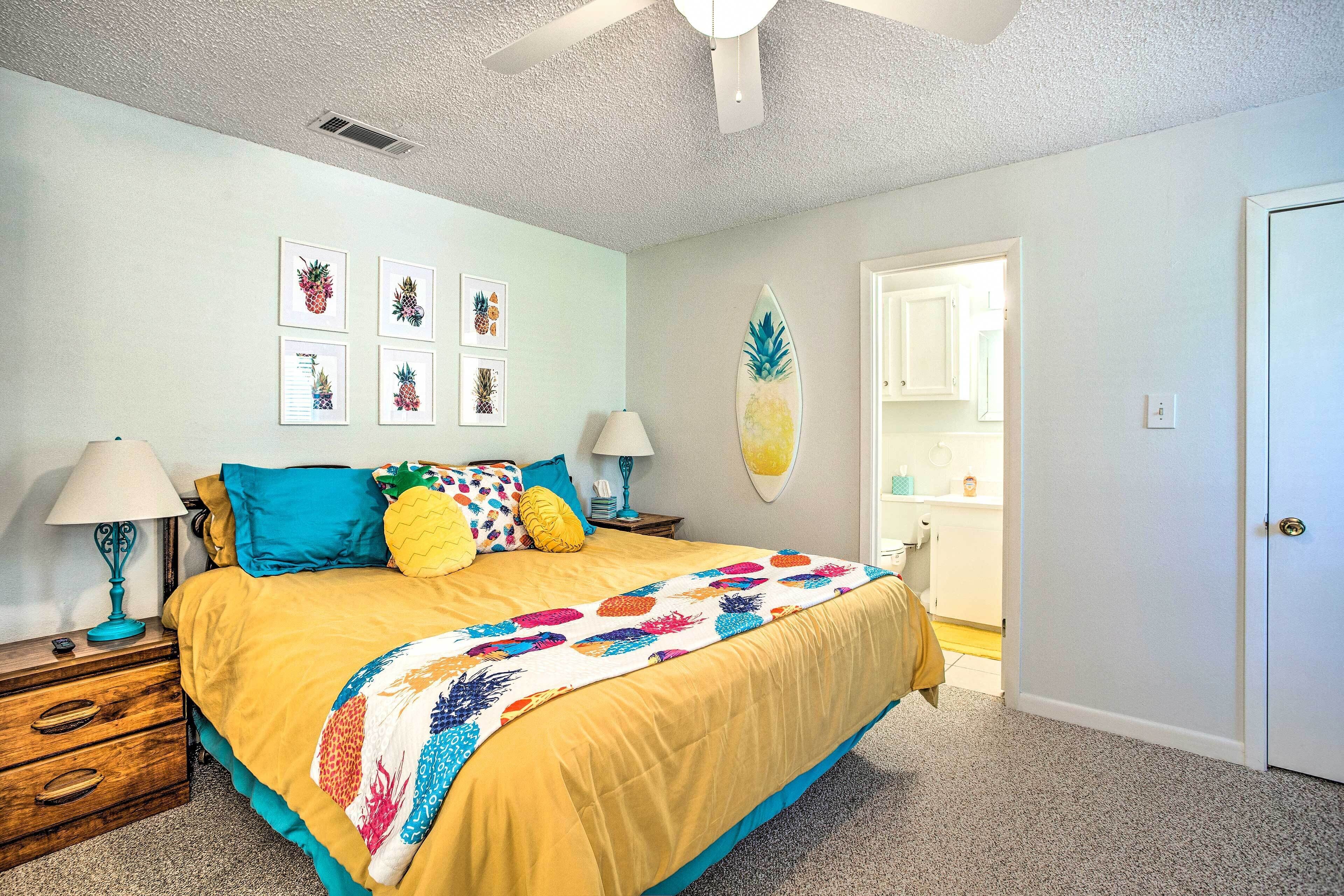 A bedroom with a bed, nightstands, a ceiling fan, and wall art.