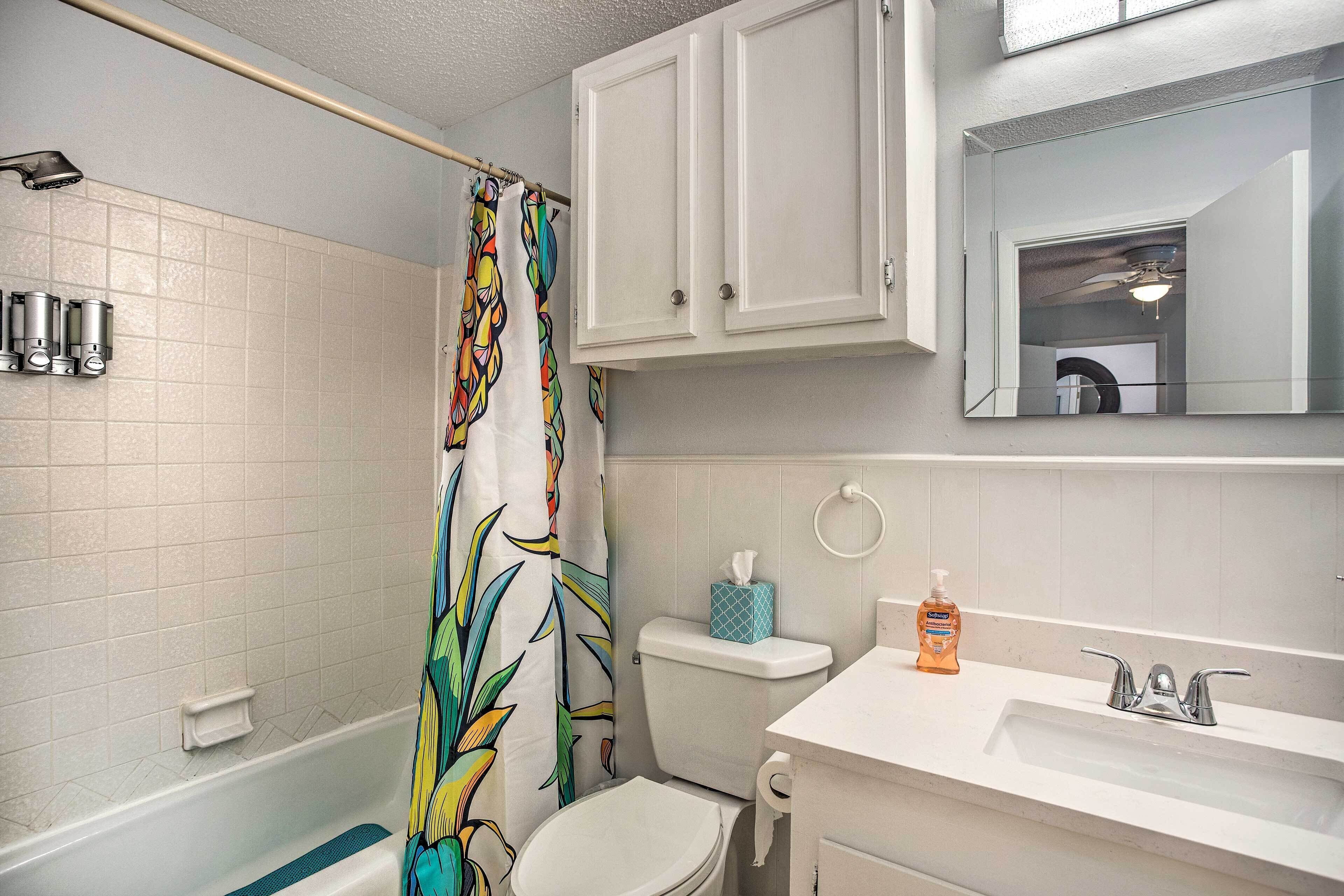 A bathroom with a shower, toilet, sink, and a mirror.