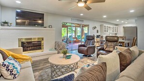 A spacious living room with a fireplace, comfortable seating, and a ceiling fan. - Cedar Creek Lake Home: Private Dock & Hot Tub (Mabank)