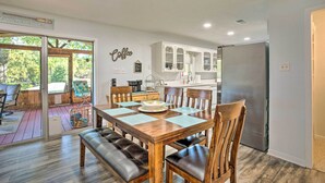 A dining area with a wooden table and chairs, a bench, and a kitchen in the background. - Cedar Creek Lake Home: Private Dock & Hot Tub (Mabank)