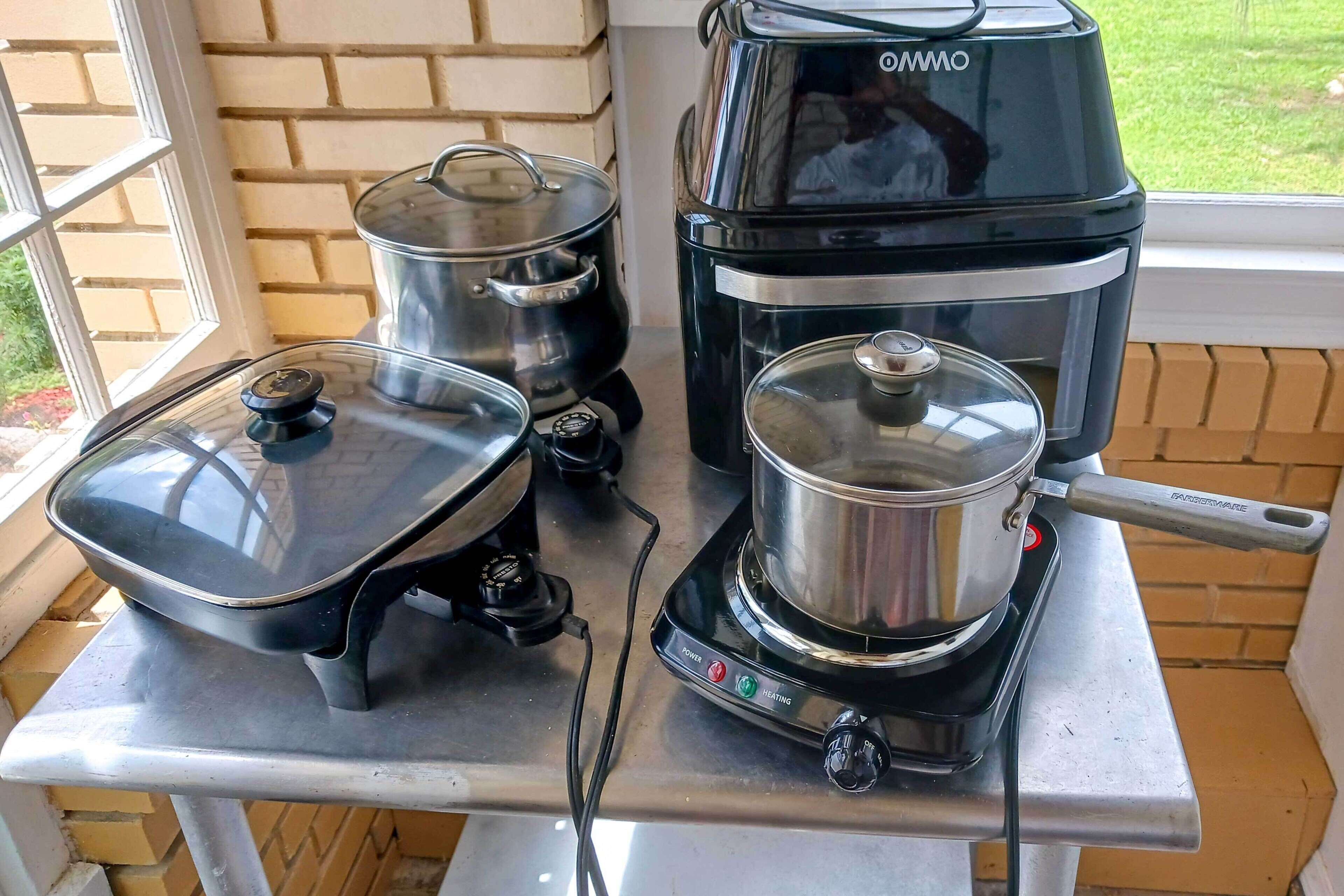 A kitchen area with a stove, a pot, and a coffee maker on a countertop.