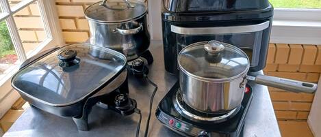 A kitchen area with a stove, a pot, and a coffee maker on a countertop.