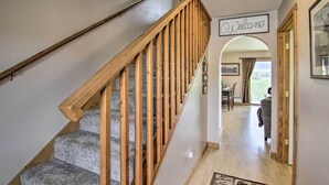 A wooden staircase with a 'Welcome' sign, leading to a room with a dining area and a view of the outdoors.
