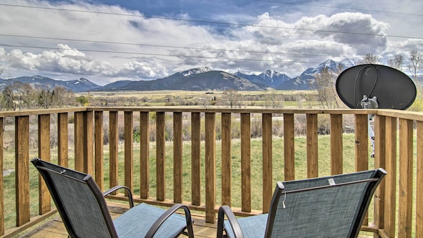 A wooden deck with two chairs and a satellite dish, overlooking a mountainous landscape.