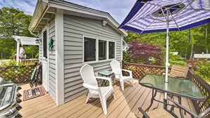 A deck with a table and chairs, a small shed, and a patio umbrella. - Charming East Boothbay Cottage w/ Large Yard! (East Boothbay)
