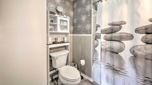 A bathroom with a toilet, a sink, and a shower curtain with a rock design. - Charming East Boothbay Cottage w/ Large Yard! (East Boothbay)