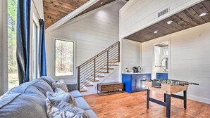 Ein geräumiges Wohnzimmer mit einer Holztreppe, einer Couch und einem Kicker.