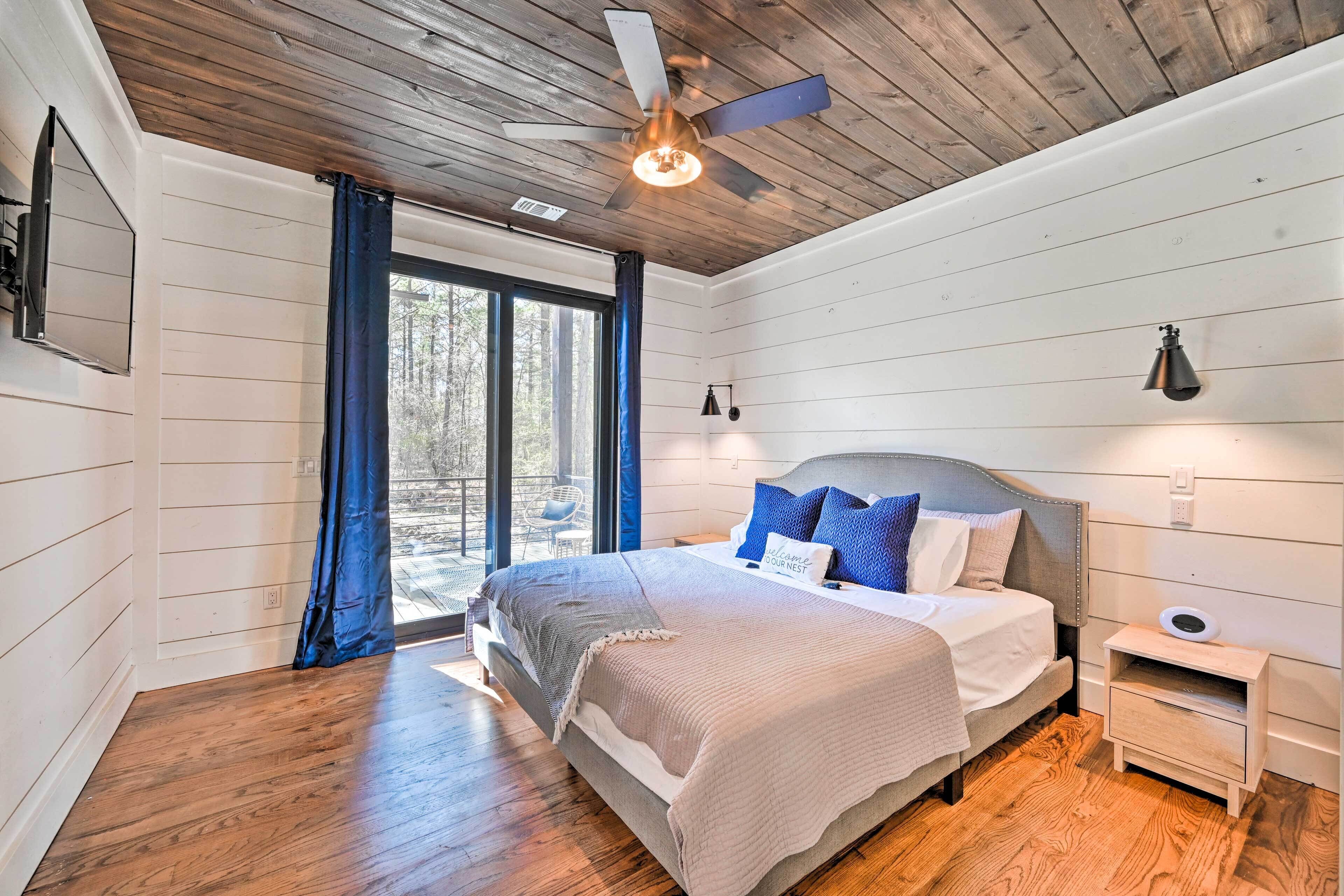 A bedroom with a wooden ceiling, a bed with a headboard, a nightstand, and a window with curtains.
