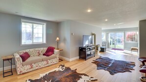 A living room with a sofa, a television, a leather rug, and a large window. - Stunning Lakeside House w/ Deck + Water Views (Lakeside)