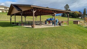 A covered picnic area with benches and tables, surrounded by grass and trees. - Stunning Lakeside House w/ Deck + Water Views (Lakeside)