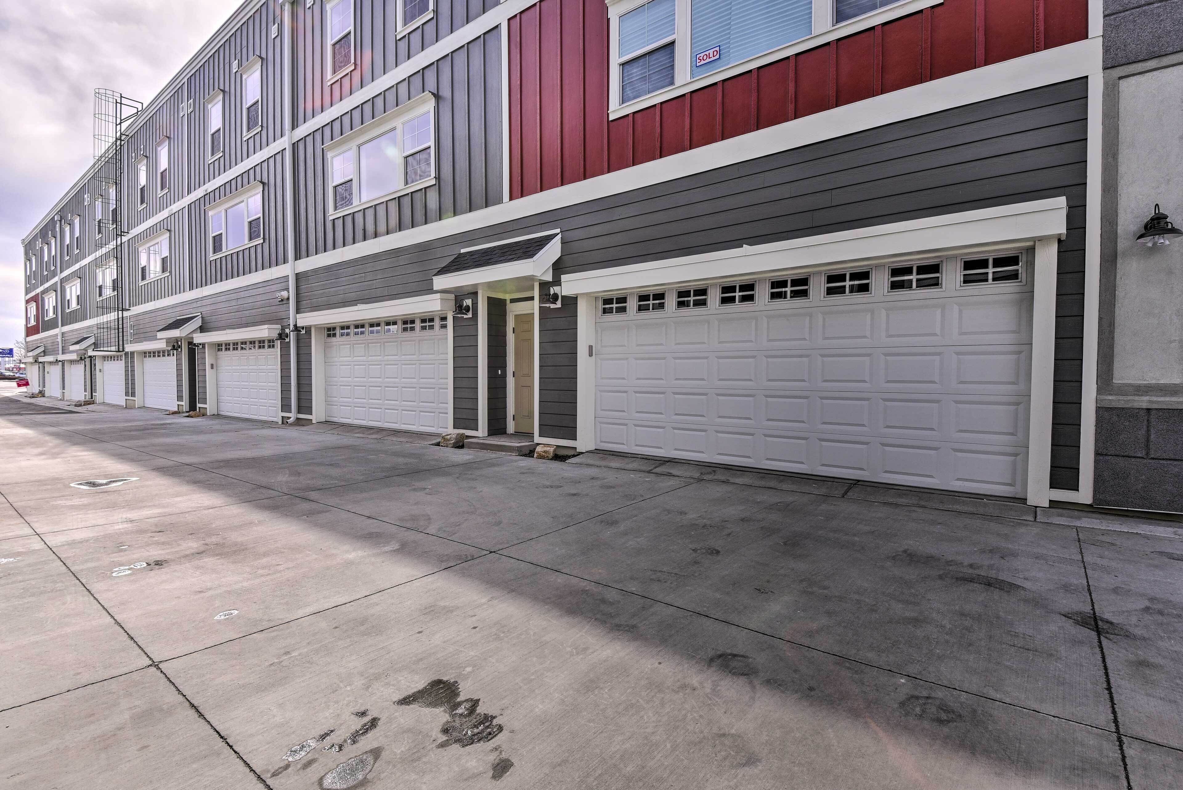 A multi-story residential building with a row of garage doors and a concrete driveway.