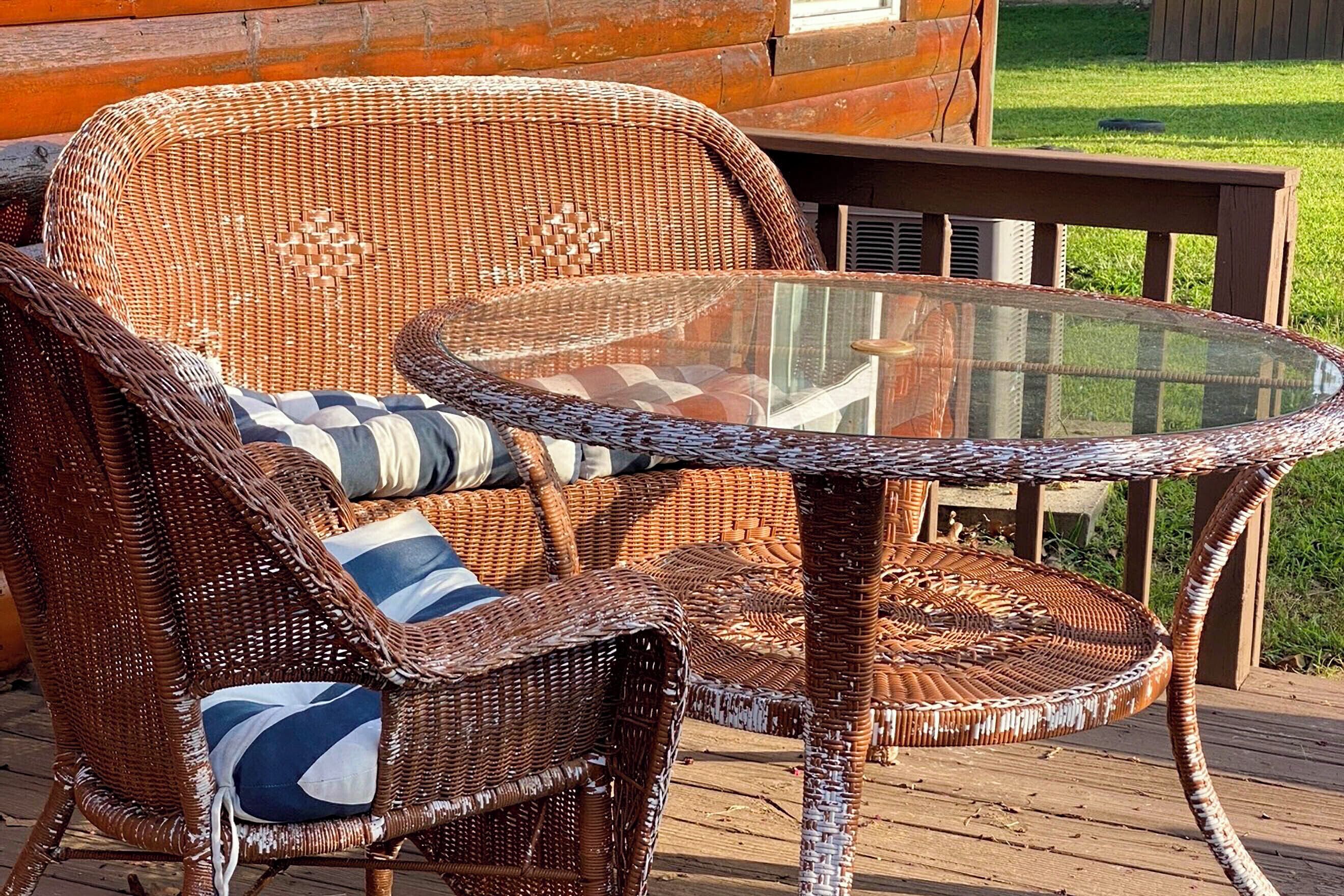 Wicker furniture with cushions, a glass-top table, and a wooden deck.
