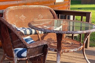 Mobiliario de mimbre con cojines, una mesa con superficie de vidrio y una terraza de madera.