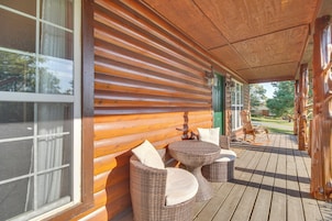 Una terraza de madera con muebles de mimbre y vistas del entorno.