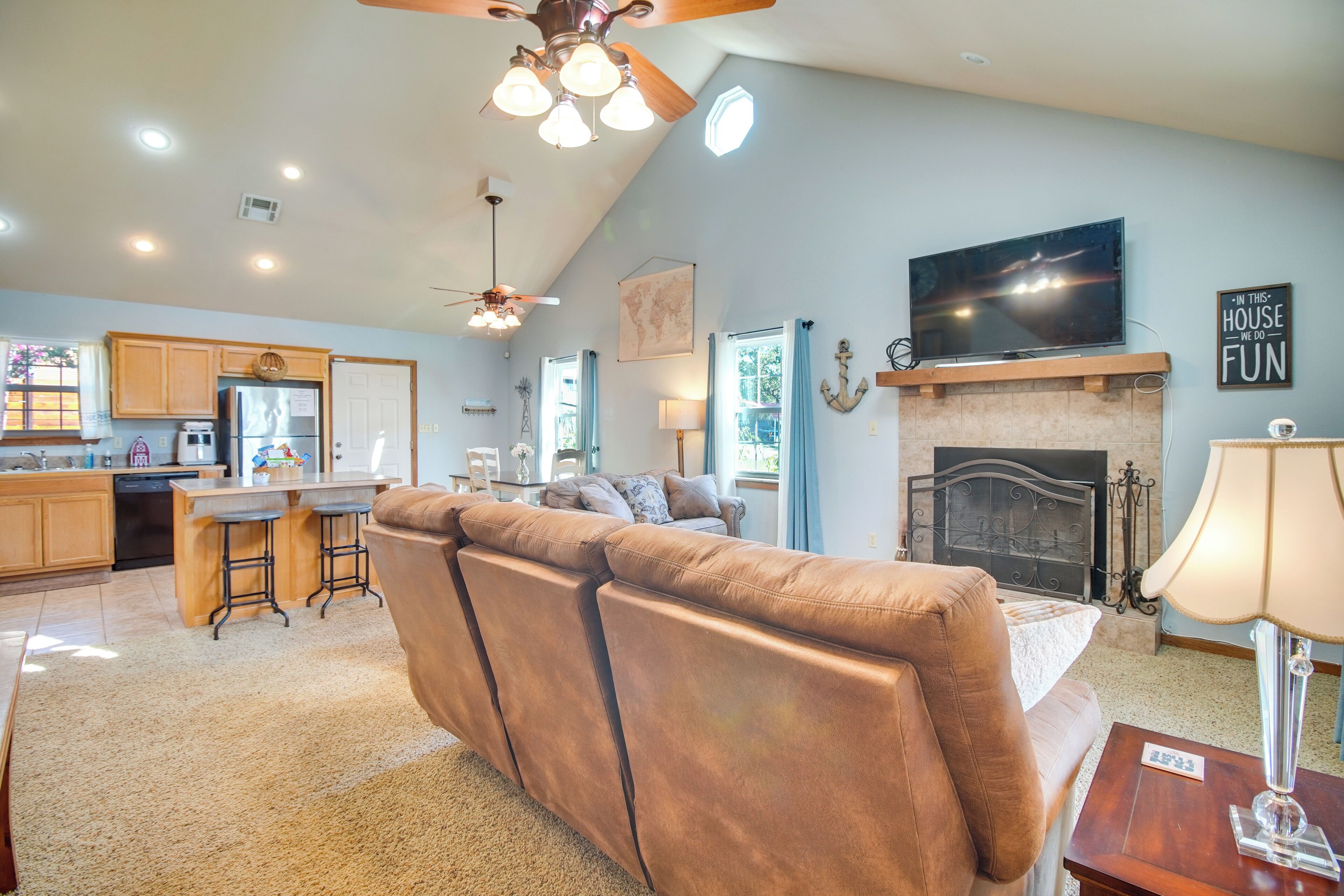 A spacious living room with a large brown sectional sofa, a fireplace, and a television mounted above it.