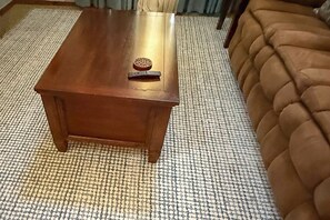 A wooden coffee table with a coaster and a remote control on it, placed on a patterned carpet. - Incredible Log Home: 1 Mile From Lake Tenkiller (Vian)