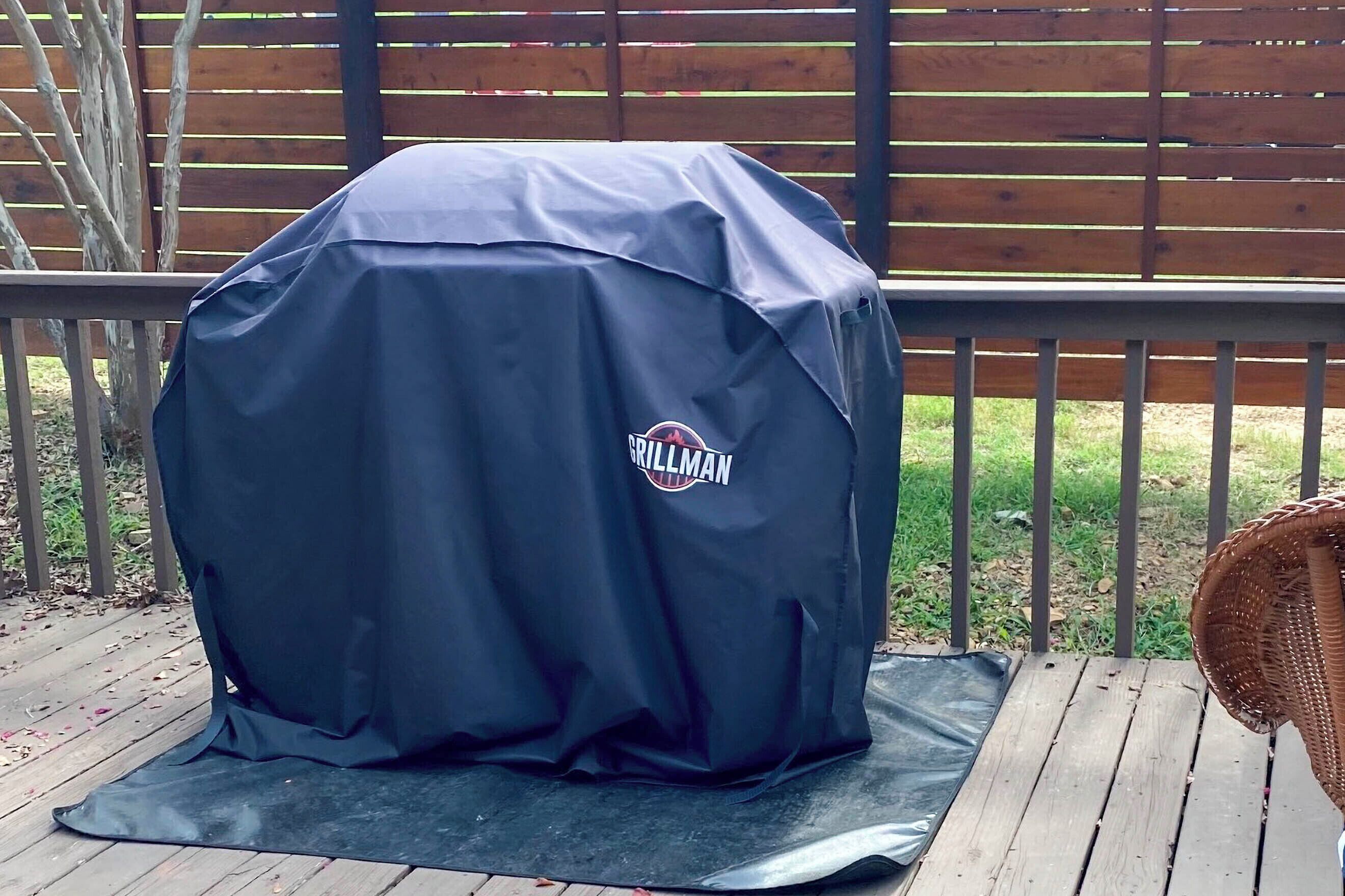 A grill with a brand logo, placed on a mat on a wooden deck.