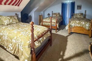 Un dormitorio con dos camas de madera, un ventilador de techo y un cuadro enmarcado en la pared.