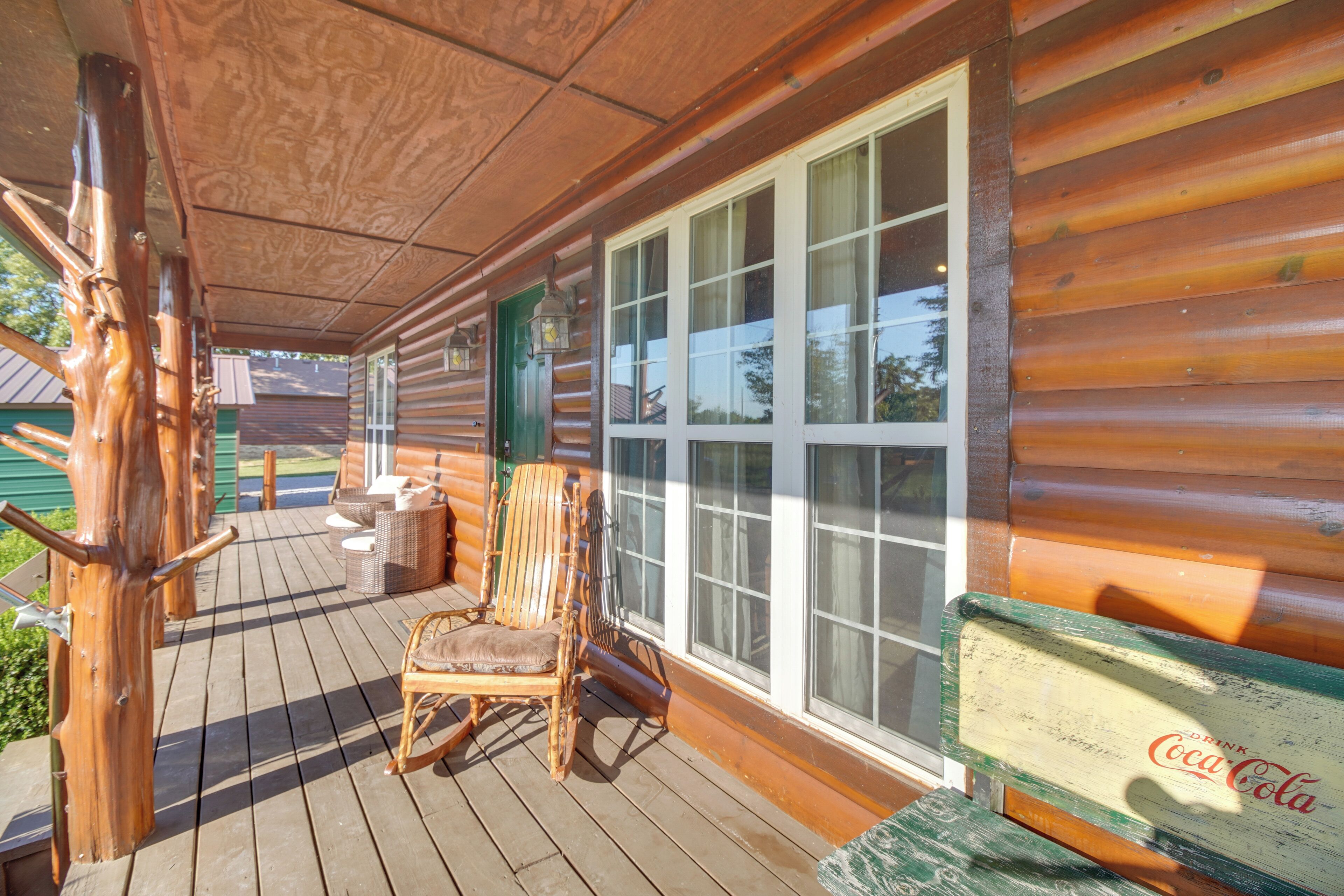Una terraza de madera con muebles de mimbre y un letrero de Coca-Cola.