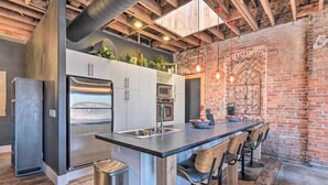 A modern kitchen with stainless steel appliances, a central island with bar stools, and exposed brick walls. - Upscale Loft in the Heart of Dtwn Springfield (Springfield)