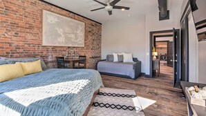 A bedroom with a brick wall, a ceiling fan, a bed with a patterned blanket, a sofa with pillows, and a rug. - Upscale Loft in the Heart of Dtwn Springfield (Springfield)
