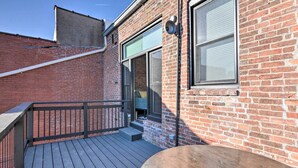 A wooden deck with a metal railing, a brick building with a window, and a door leading to a covered area. - Upscale Loft in the Heart of Dtwn Springfield (Springfield)