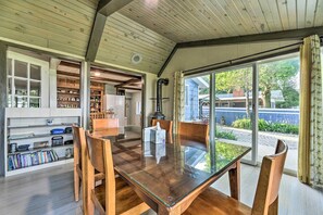 Un vaste espace dédié à la salle à manger, avec une table en verre et des chaises en bois, un plafond en bois et une vue sur l’extérieur.