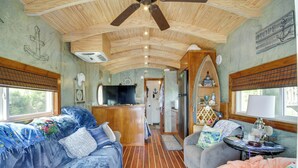 A cozy interior with a wooden ceiling, a kitchen area, and a living space with a sofa and a table. - Bay St Louis Houseboat 6 Mi to Old Town & Beach! (Bay St Louis)