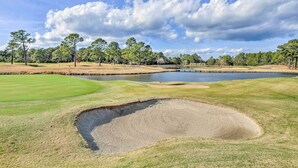 A golf course with a water hazard, sand bunkers, and a flag marking the hole. - Screened Porch + Golf On-site: Myrtle Beach Condo (Myrtle Beach)