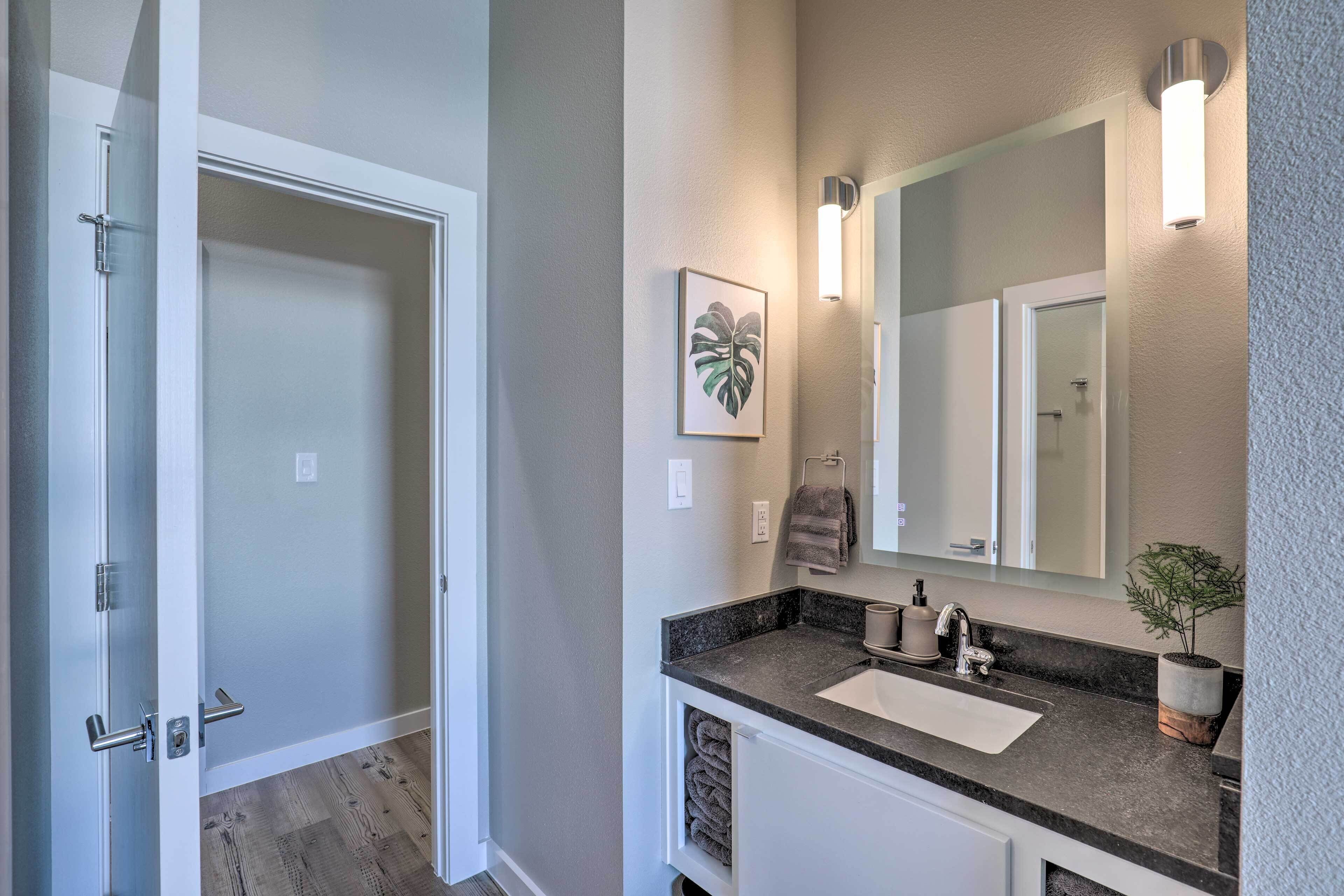 A modern bathroom with a large mirror, a sink, and a towel rack.