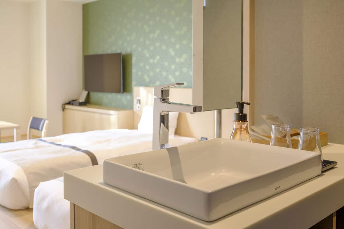 A hotel bathroom with a white sink, a mirror, and toiletries on the counter.