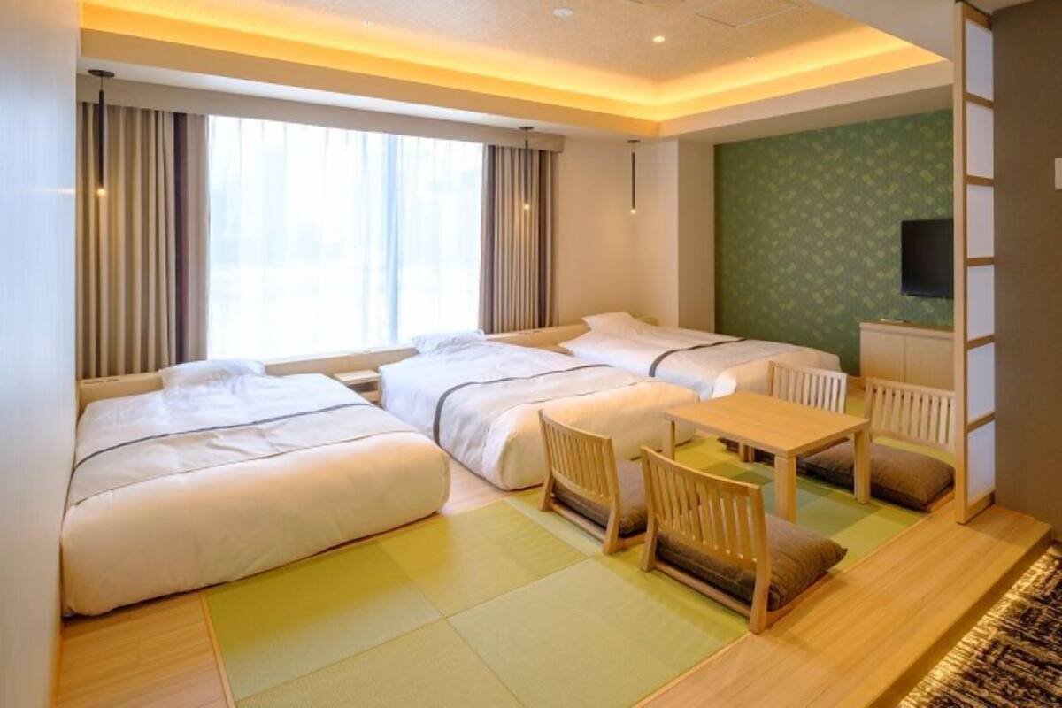 A hotel room with two beds, a small table, and a TV.