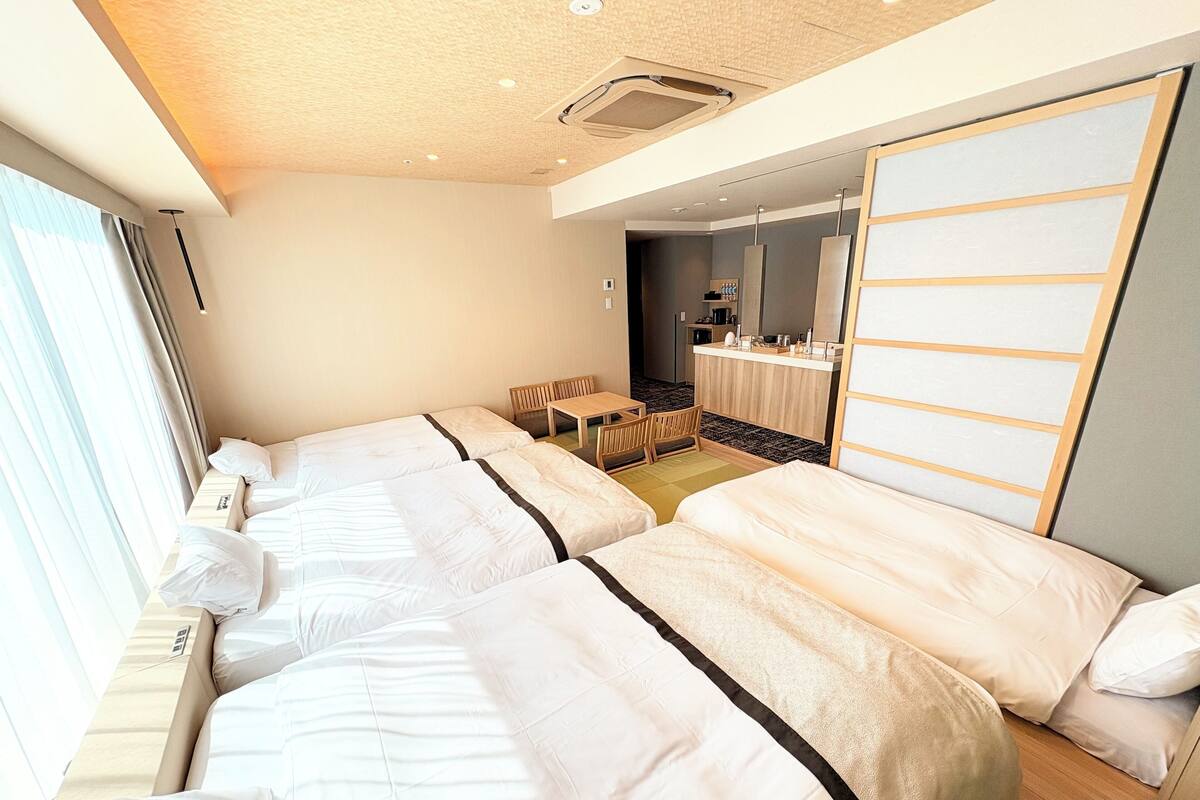 A hotel room with two beds, a desk, and a bathroom visible through an open door.