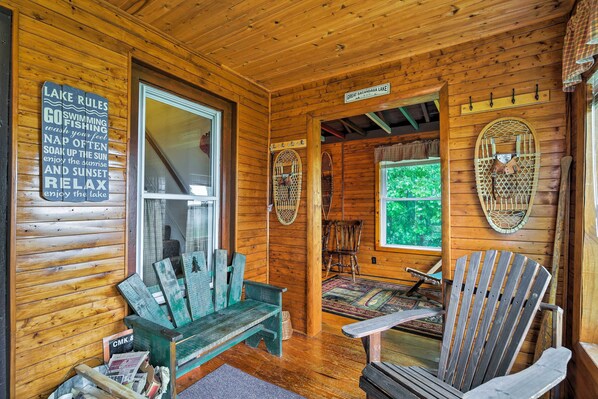 L’intérieur d’un chalet en bois, avec un banc en bois, une chaise et un panneau indiquant les règles à respecter au bord du lac.