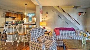 A cozy living room with plaid furniture, a coffee table, and a vase of sunflowers. - Northville Lakefront Escape w/ Deck: Walk to Lake (Northville)