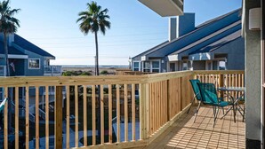 Eine Holzterrasse mit Blick auf einen Strand und ein Haus.